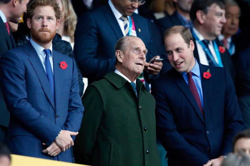 Prinz Harry (l) und sein Bruder Prinz William (r) stehen mit ihrem Großvater Prinz Philip vor Beginn des Rugby World Cup Finales zwischen Neuseeland und Australien im Twickenham Stadion. Werden sich die beiden Brüder wieder versöhnen?