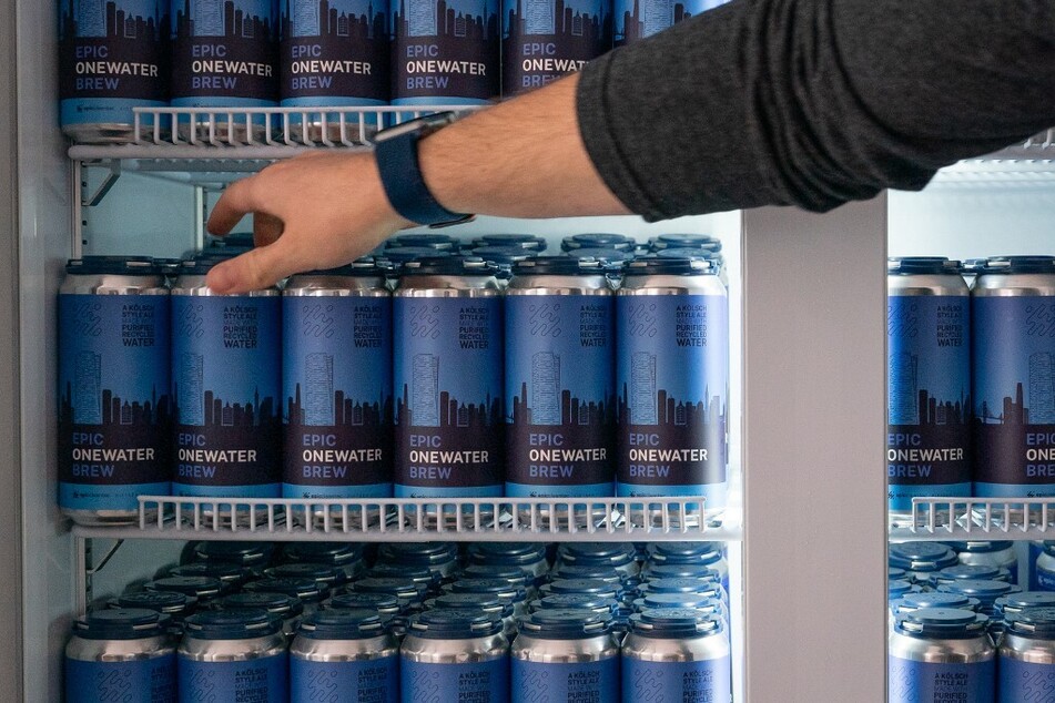 Aaron Tartakovsky, co-founder and CEO of Epic Cleantec, reaches into a refrigerator of beers brewed with recycled wastewater at the company’s headquarters.