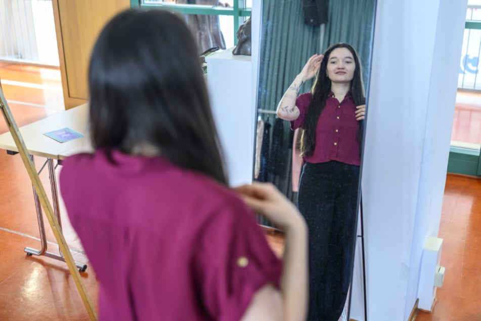 Lea Peters (26) hat eine Bluse anprobiert und betrachtet sich im Spiegel.