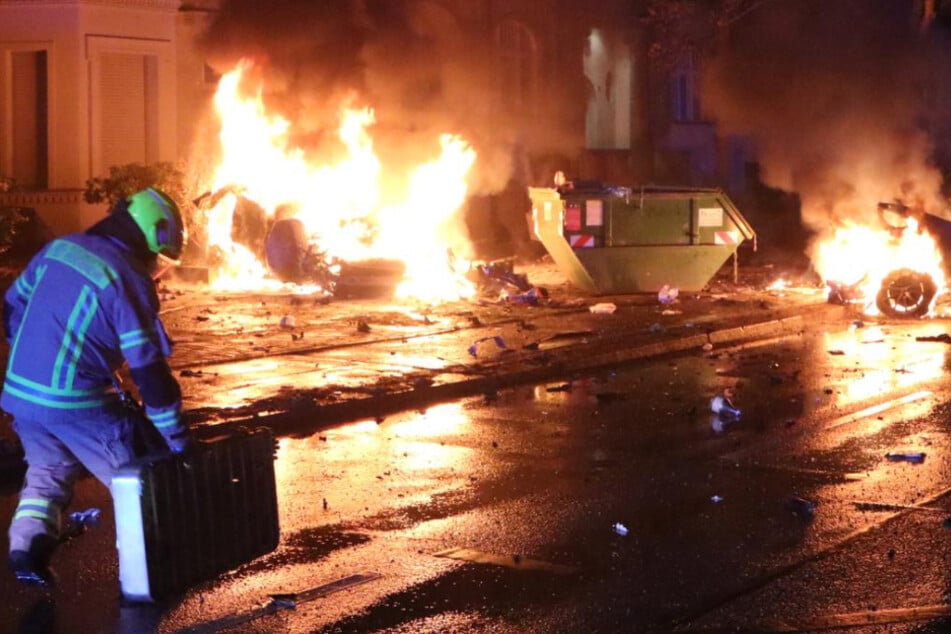 Ein Feuerwehrmann steht vor dem brennenden Wagen.