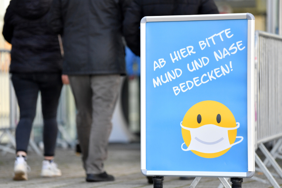 "Ab hier bitte Mund und Nase bedecken" steht auf einem Schild. (Symbolbild)