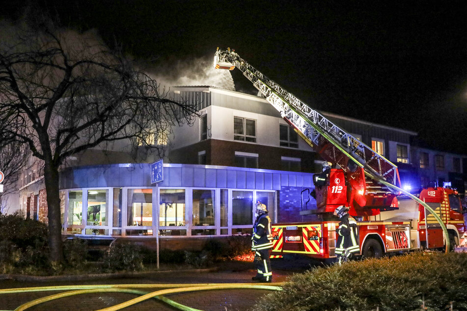Einsatzkräfte der Feuerwehr löschen mit einer Drehleiter den Brand in dem Altenheim.