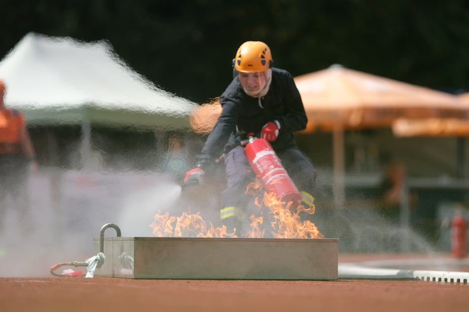 Eine Feuerwehrsportlerin trainiert im Hafenstadion das Löschen eines Flüssigkeitsbrandes.