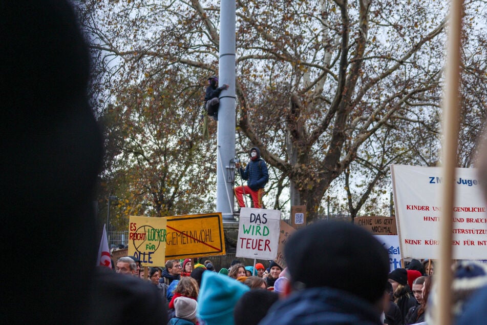 Demo-Teilnehmer klettern vor dem Neuen Rathaus in der Dresdner Altstadt auf einen Fahnenmast.