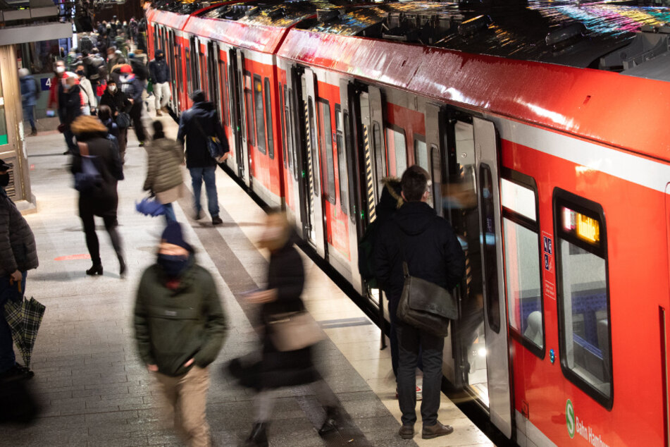 Mit Mund-Nasen-Schutz sind Fahrgäste am Hauptbahnhof auf einem S-Bahnsteig unterwegs.