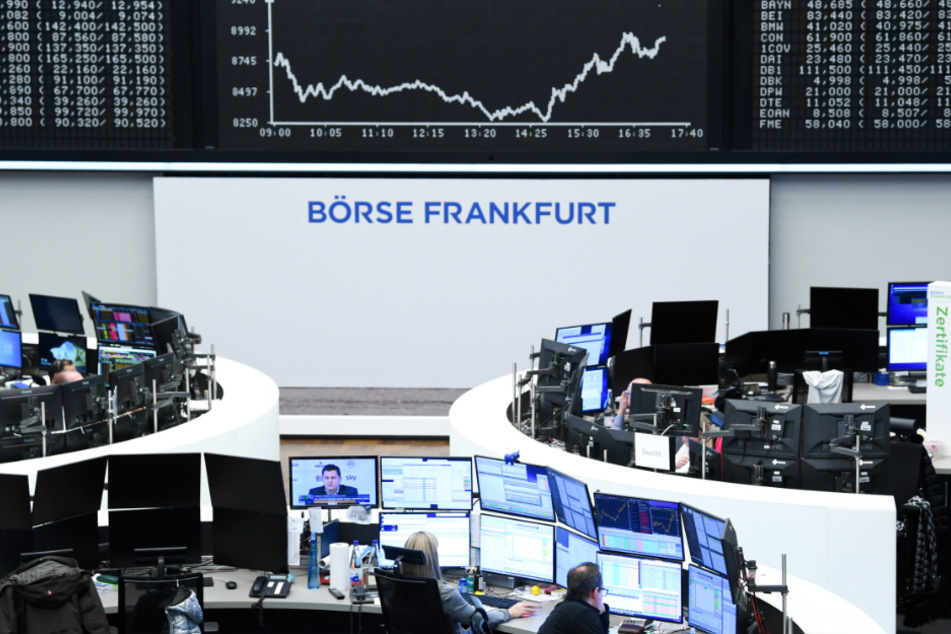 Aktienhändler arbeiten im Handelssaal der Frankfurter Wertpapierbörse vor der Anzeigetafel mit der Dax-Kurve.