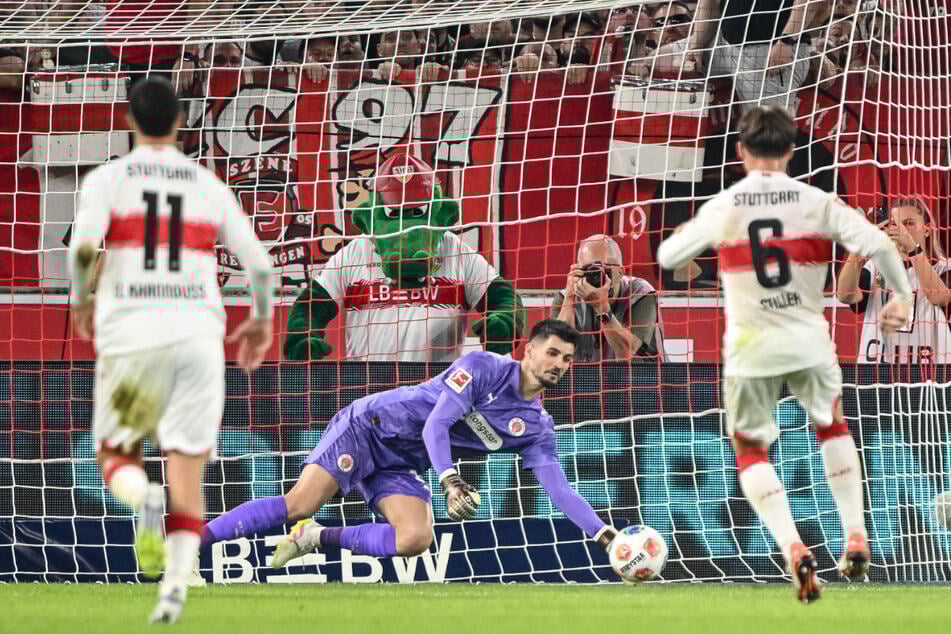 St. Paulis Keeper Nikola Vasilj hält den kläglich geschossenen Elfmeter von Angelo Stiller (r).