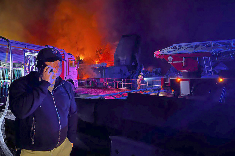 Das Foto zeigt Gouverneur Michail Raswoschajew, während Rauch und Flammen aus einer brennenden Werft in Sewastopol aufsteigen.