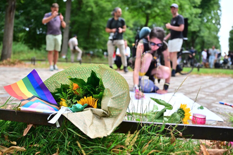 Menschen hinterlassen im Gedenken an die Opfer Blumen und Transparente am Tatort.