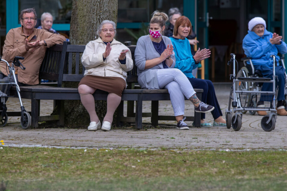 Bewohner und Pflegekräfte applaudieren nach kleinen Konzert vor dem AWO Seniorenhaus Schelfwerder, das wegen der Corona-Krise für Besucher gesperrt ist.