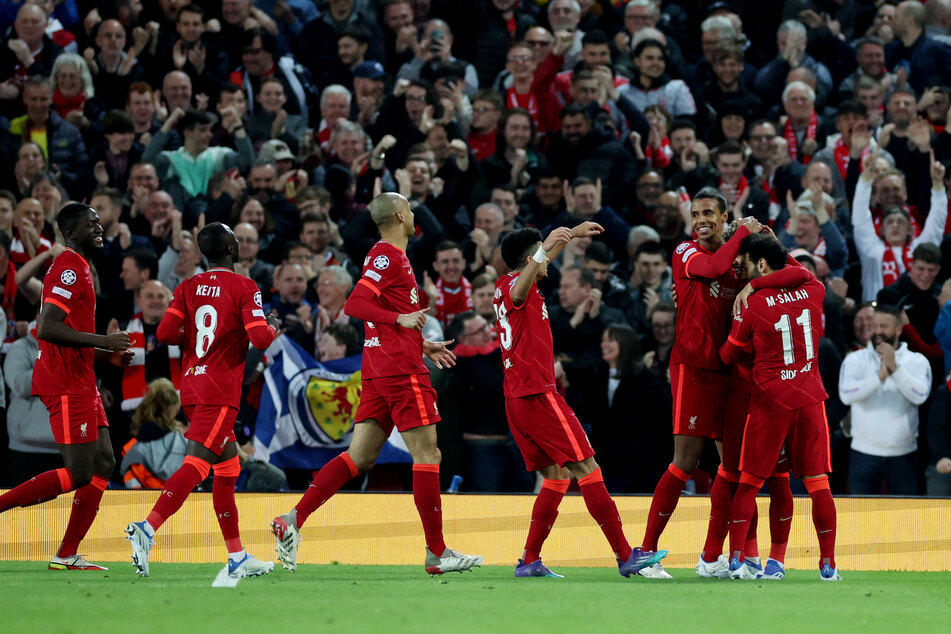 Liverpool players mob Roberto Firmino after the Brazilian forward scored his team's third goal at Anfield.