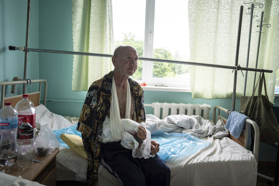 Witali Schpalin sitzt auf einem Bett in einem Krankenhaus, nachdem er auf der Flucht in einem Boot aus einem überfluteten Dorf am linken Ufer des Dnepr-Flusses angeschossen wurde.