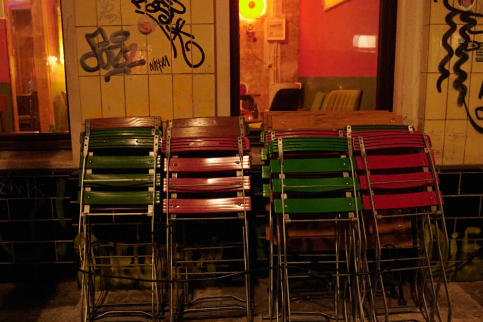 Kurz nach der Sperrstunde stehen zusammengeklappte Stühle vor einer Bar in Neukölln.