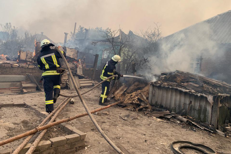 Einsatzkräfte der Feuerwehr löschen den Brand in der Kleingartensiedlung.
