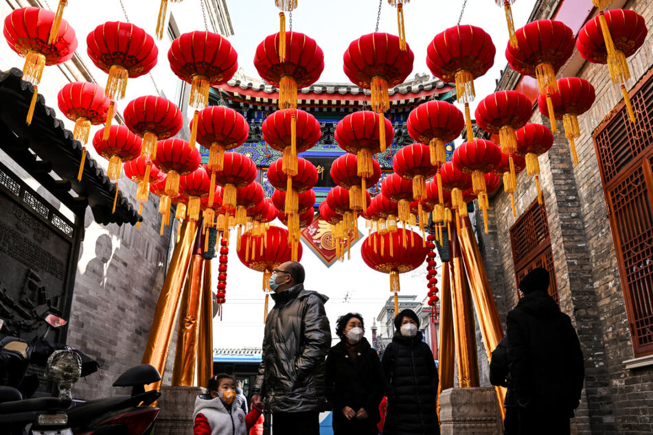 Masked residents in Beijing walk under lanterns ahead of the Lunar New Year.