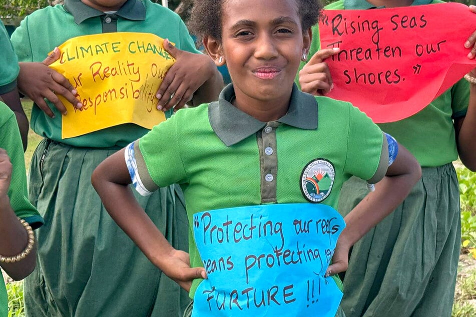 Schoolchildren from the Suango Mele primary and secondary school, located in the village of Mele, north of the Vanuatu capital of Port Vila, hold signs as they pose for a photograph on July 24, 2025.