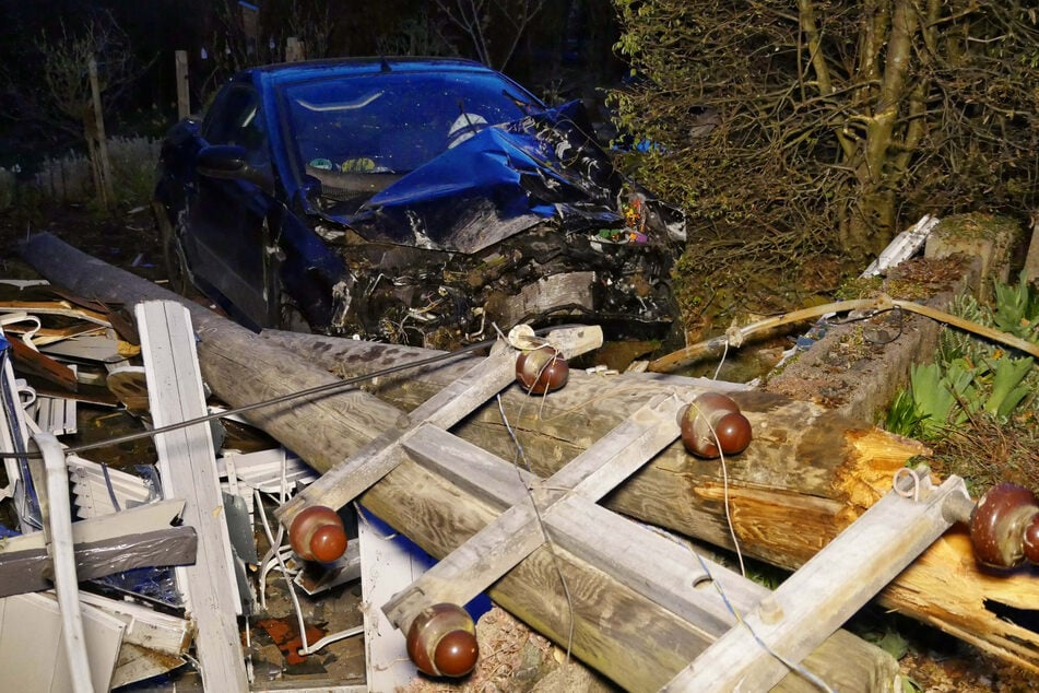 Ein zerstörtes Auto steht an einem umgestürzten Strommast in Siegen (Nordrhein-Westfalen).