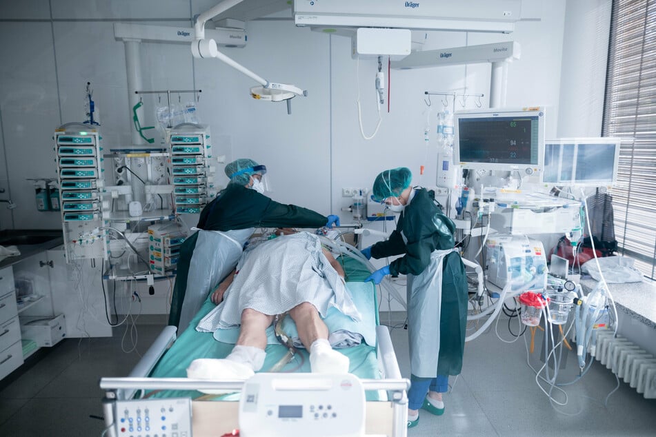 Mitarbeiterinnen der Pflege in Schutzausrüstung betreut einen Corona-Patienten.