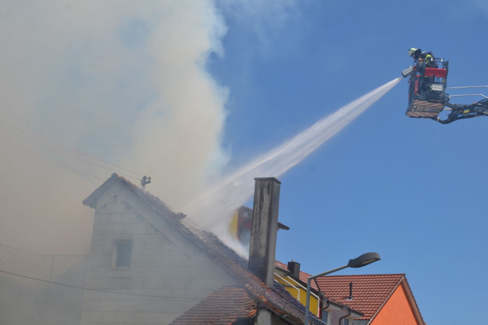 Ein Feuerwehrmann löscht von einer Drehleiter aus.
