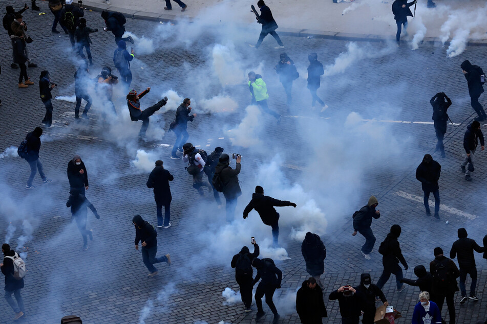 Pariser Demonstranten treten während ihres Protests Tränengaskanister weg.