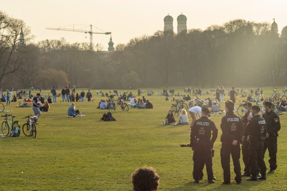 Polizisten kontrollieren im Englischen Garten in München, ob die Menschen die wegen Corona vorgeschriebenen Abstände einhalten.
