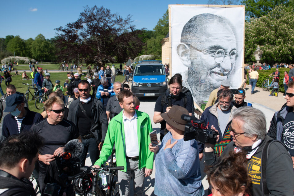 Im Hintergrund ist eine Zeichnung von Mahatma Gandhi, dem Helden der indischen Unabhängigkeitsbewegung, zu sehen.