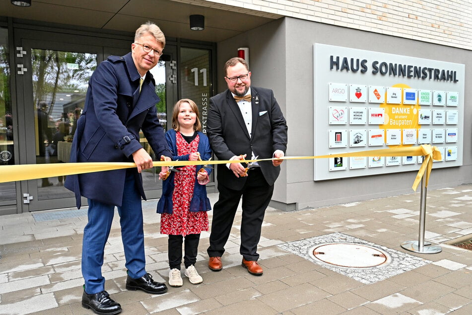 Uniklinikum-Vorstand Uwe Platzbecker, Mila und Andreas Führlich (v.l.) durchschneiden das Eröffnungsband.