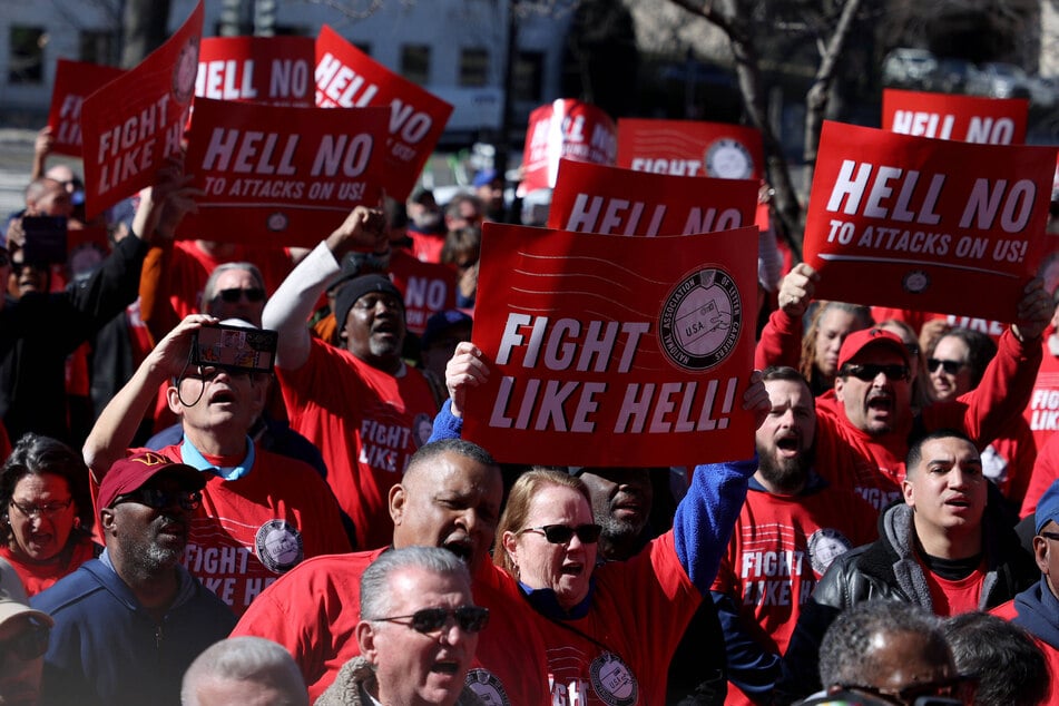 US Postal Service workers raise signs during a rally on Capitol Hill against the Trump administration's plans to significantly restructure the agency.