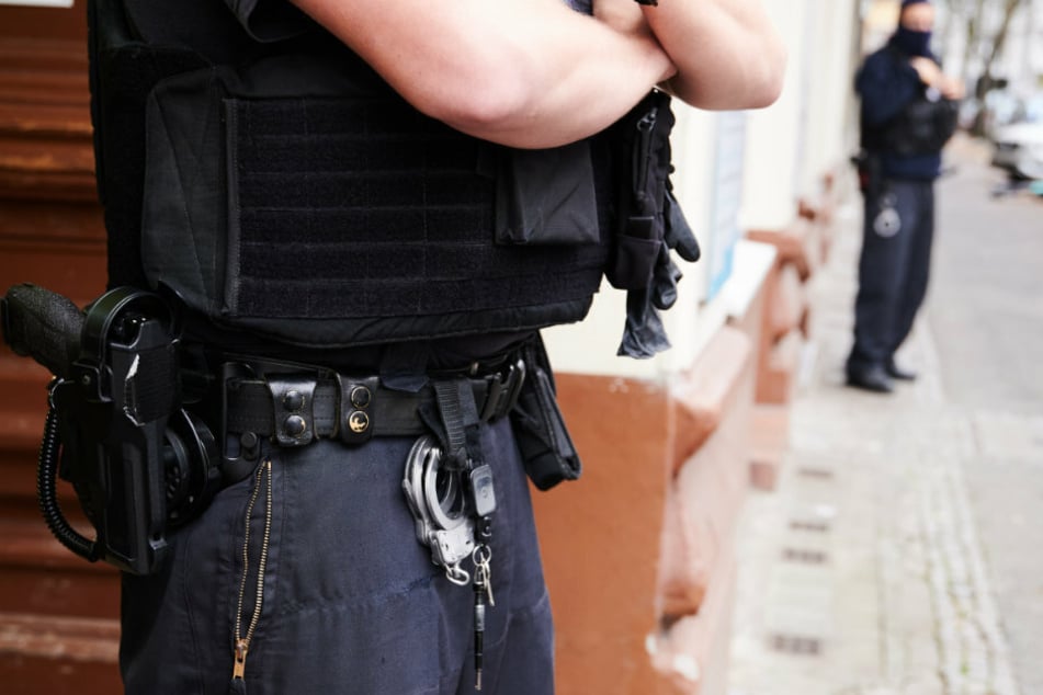 Ein Polizist steht bei einem Einsatz in einem Hauseingang.
