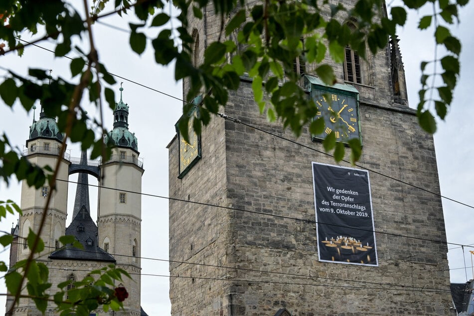 Ein Plakat mit der Aufschrift "Wir gedenken der Opfer des Terroranschlags vom 09. Oktober 2019" hängt am Roten Turm auf dem Marktplatz.