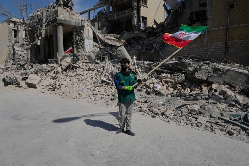 Teheran: Ein Junge schwenkt eine iranische Flagge vor einer Polizeieinrichtung, die bei einem früheren Angriff der amerikanisch-israelischen Militäraktion getroffen wurde.