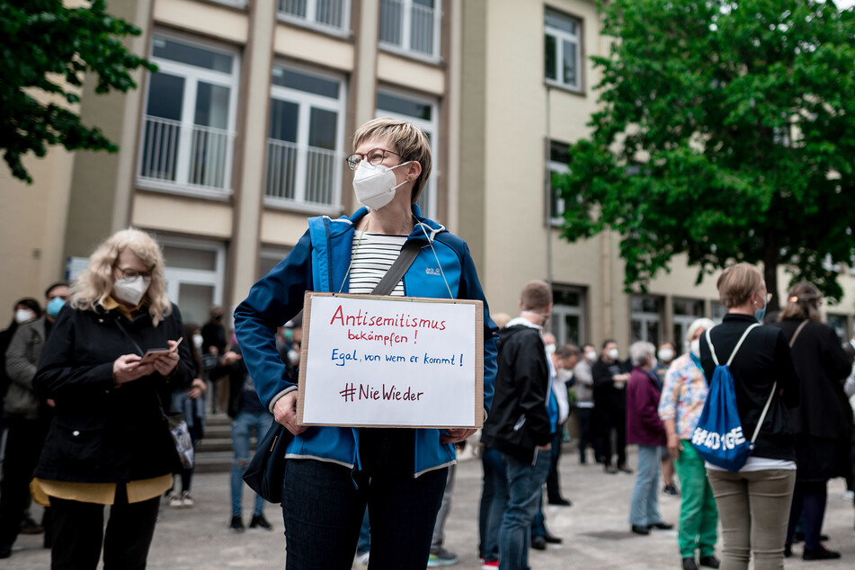 Birgit Wehrhöfer (55) trägt ein Schild, auf dem "Antisemitismus bekämpfen! Egal, von wem er kommt! #niewieder" steht.