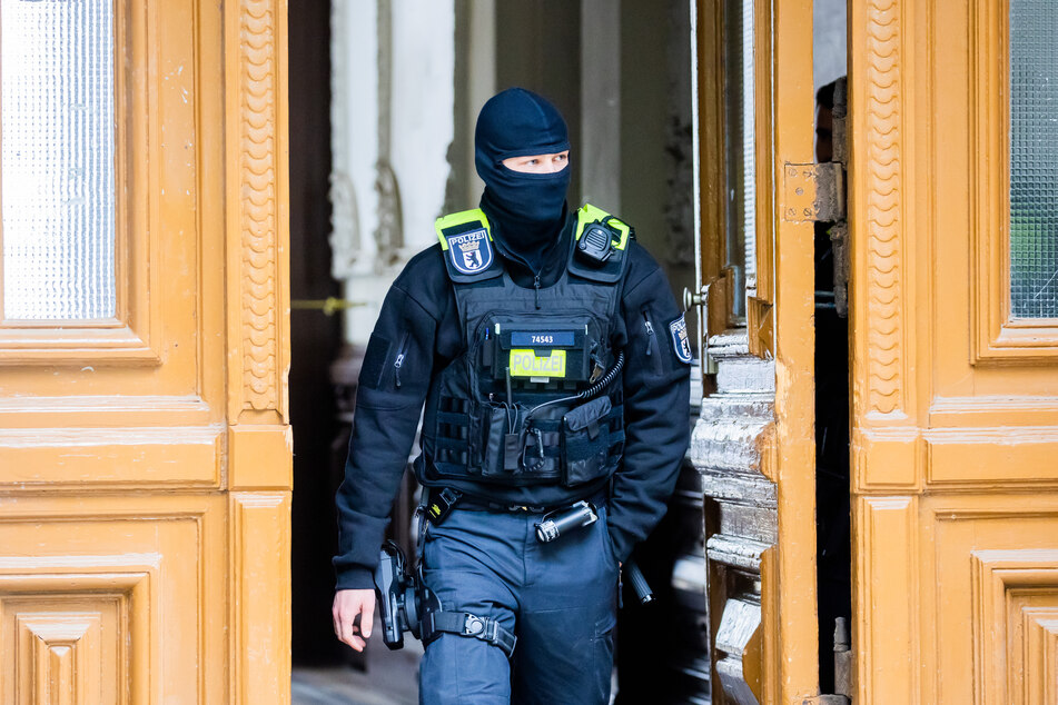 Ein Polizist steht während einer Razzia in einem Hauseingang im Berliner Ortsteil Kreuzberg.