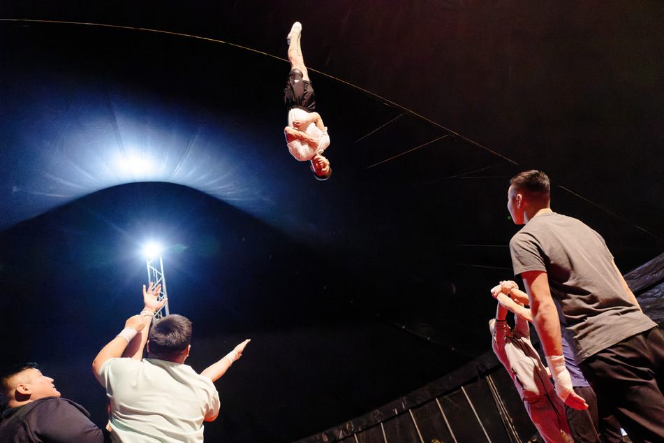 Ein Artist schwebt während der Proben kopfüber in der Luft.
