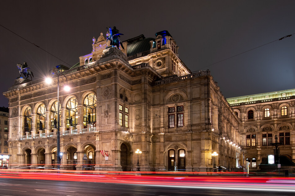 Die Lichter vorbeifahrender Autos sind vor der Wiener Staatsoper am Abend zu sehen.