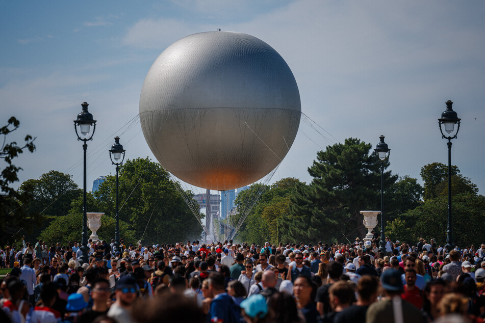 Visitors gather to watch the Paris 2024 Olympic Games cauldron attached to a balloon at the Jardin des Tuileries in Paris on Sunday, July 28, 2024.