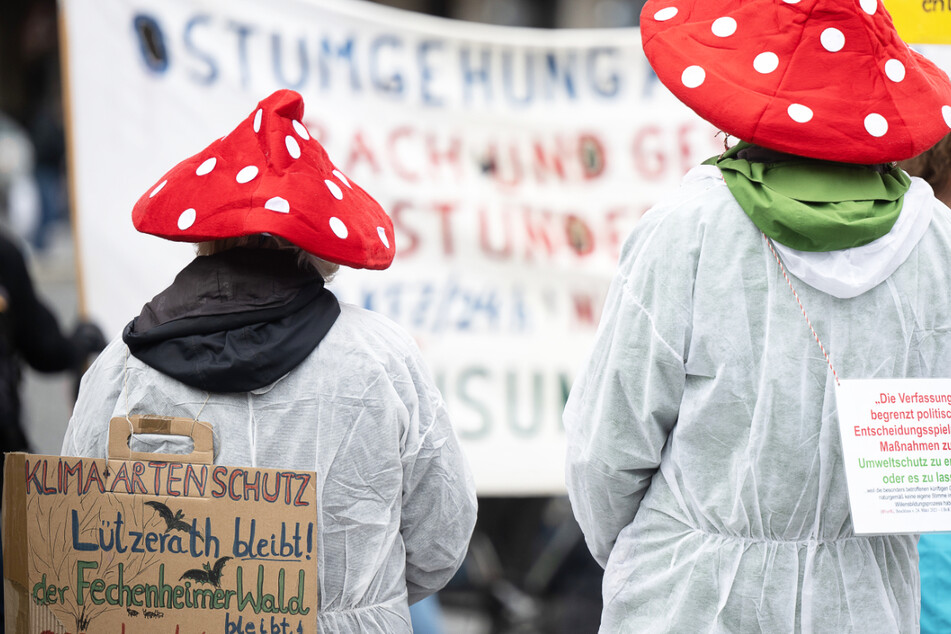 Das Foto zeigt zwei Demo-Teilnehmer mit Fliegenpilz-Hüten - der Protest am Samstag richtete sich gegen die geplante Fällung von bis zu 1000 Bäumen im Fechenheimer Wald.