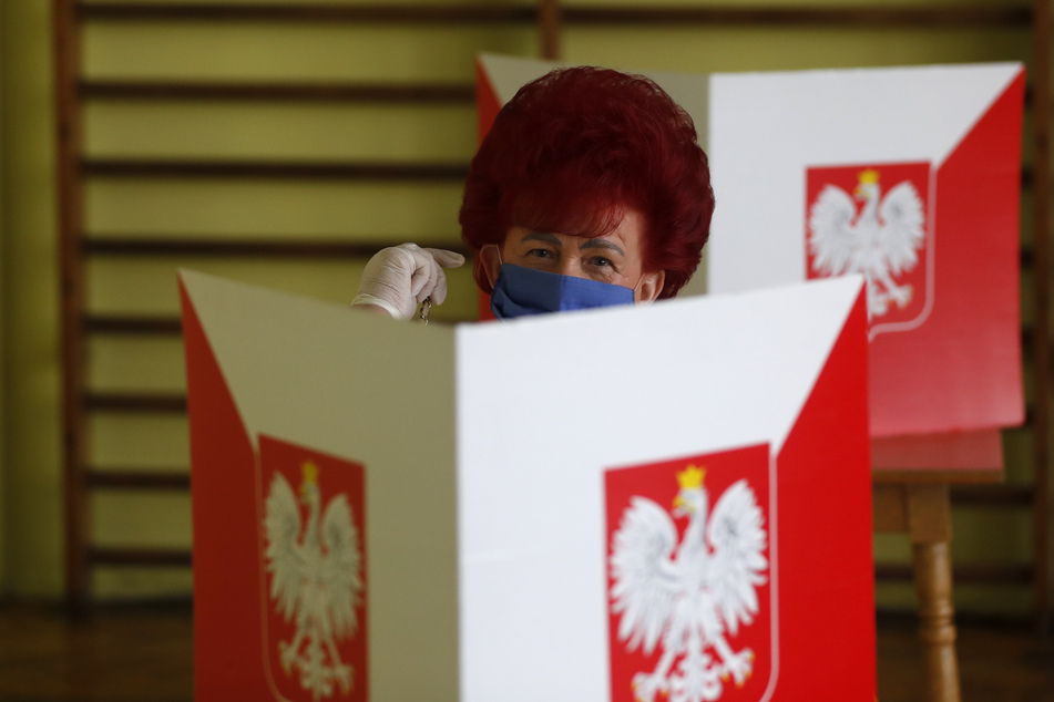 Eine Wählerin trägt in einer Wahlkabine einen Mundschutz. Um diesen abzunehmen, braucht es künftig ein ärztliches Attest.