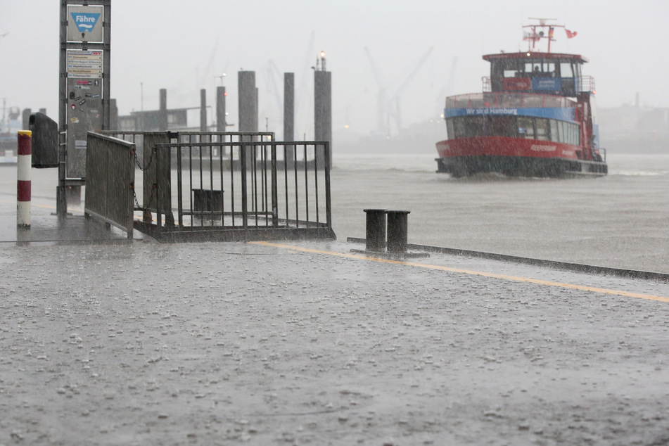 Während starkem Regen legt eine Fähre an den Landungsbrücken am Hafen an.
