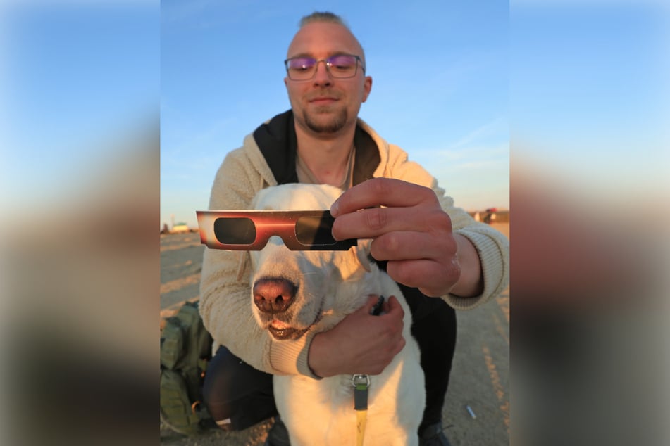 Hund Charly beobachtet die Sonnenfinsternis mit seinem Herrchen auf dem Brocken durch eine Brille.