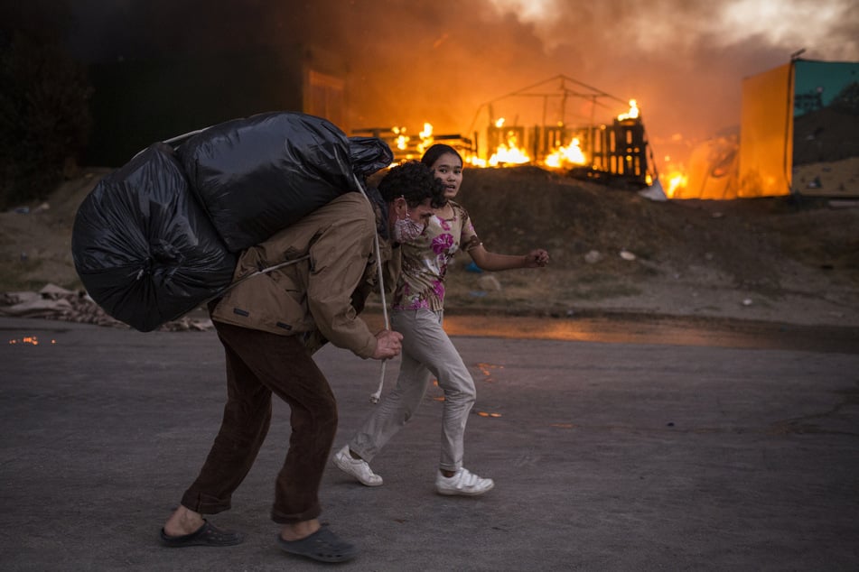 Refugees flee with their belongings from new fires in Moria camp.