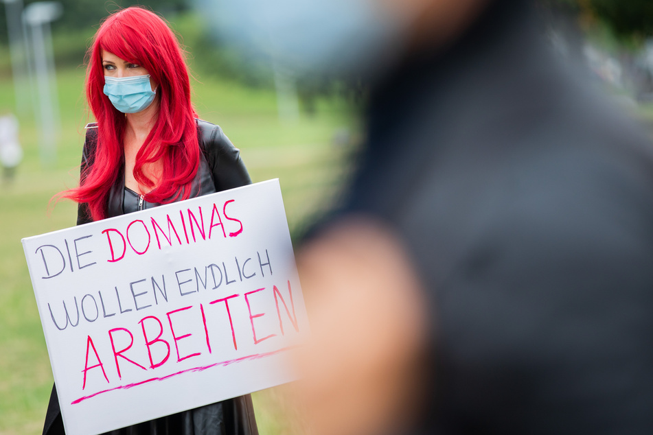 Eine Prostituierte trägt bei einer Demonstration vor dem Landtag ein Schild mit der Aufschrift "Die Dominas wollen endlich arbeiten".
