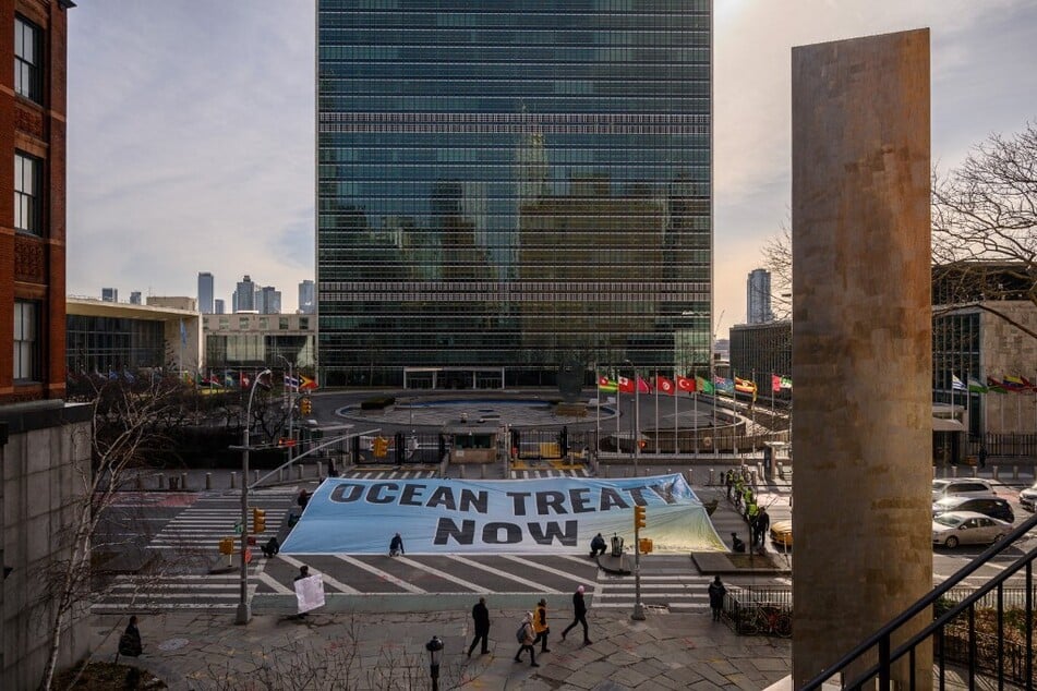 Activists from Greenpeace display a banner before the United Nations headquarters in New York during negotiations on a treaty to protect the high seas on February 27, 2023.