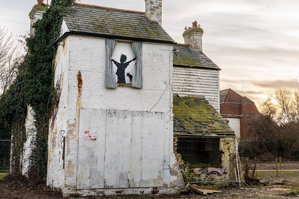 Auf der Außenwand des alten Bauernhauses sieht man das Banksy-Kunstwerk "Morning Has Broken".