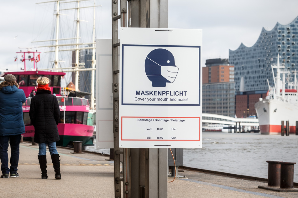 Ein Hinweisschild zur Maskenpflicht hängt auf den Landungsbrücken an der Elbe. Jogger müssen hier keine Maske mehr tragen. (Archivbild)