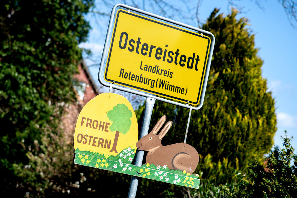 Ein Schild mit der Aufschrift "Frohe Ostern" hängt unter dem Ortsschild am Ortseingang von Ostereistedt.