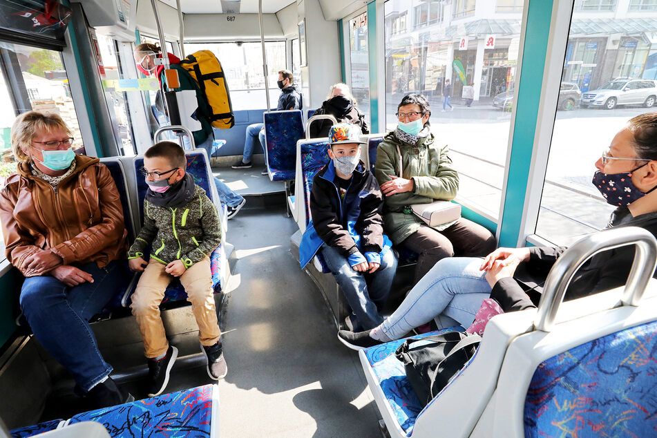 Fahrgäste sitzen mit Mund-Nasenbedeckungen in einer Straßenbahn in Rostock.