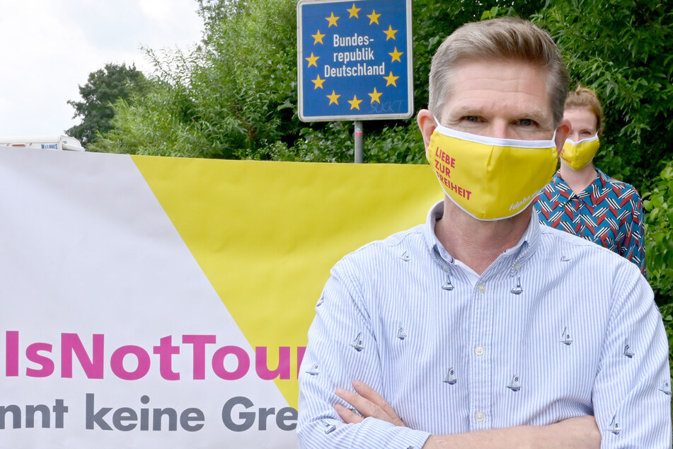 Mit einer Schutzmaske steht Heiner Garg (54), FDP-Landesvorsitzender und Gesundheitsminister von Schleswig-Holstein, bei einer Demonstration am Grenzübergang Padborg.