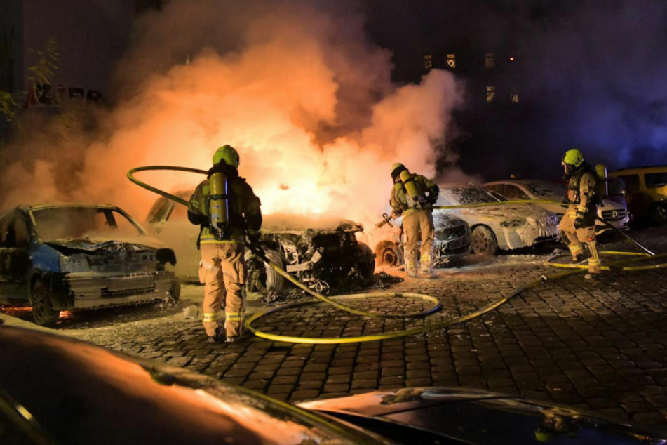 Feuerwehrleute löschen den Brand in Berlin-Mitte, bei dem insgesamt fünf Autos beschädigt oder zerstört wurden.