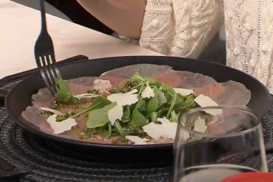 Als Vorspeise gibt es ein Kalbs-Carpaccio verfeinert mit einer Kapern-Vinaigrette, Rucola und gehobeltem Parmesan.